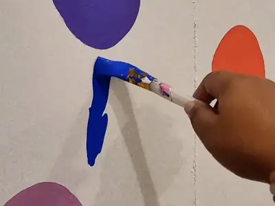 hand holding paintbrush painting on canvas